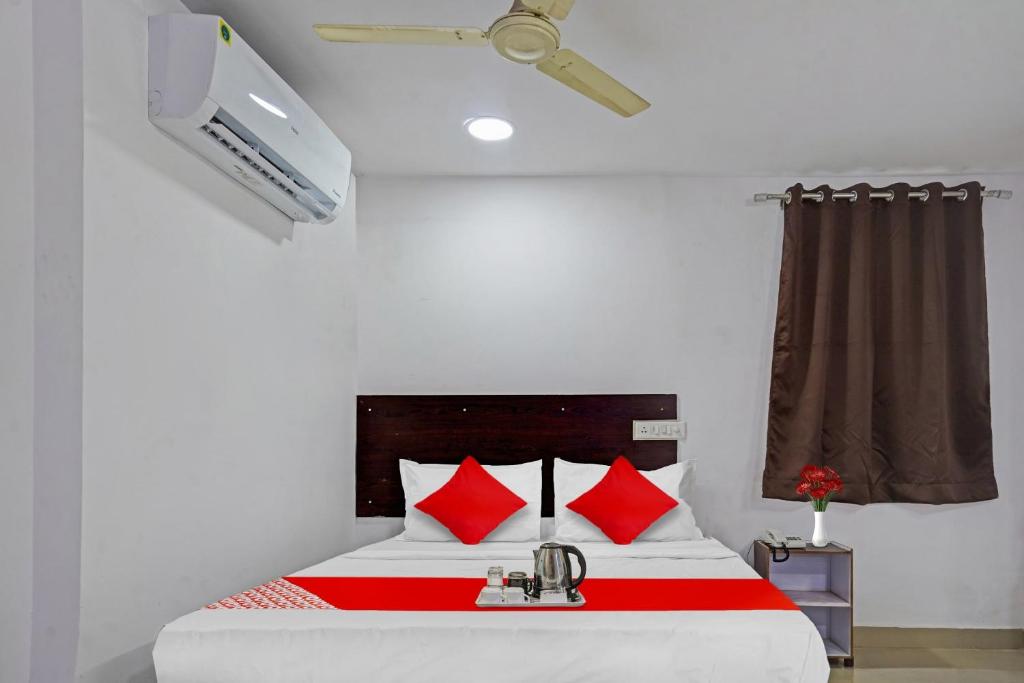 um quarto com uma cama com almofadas vermelhas e uma televisão em Sai Krishna Residency em Vijayawada
