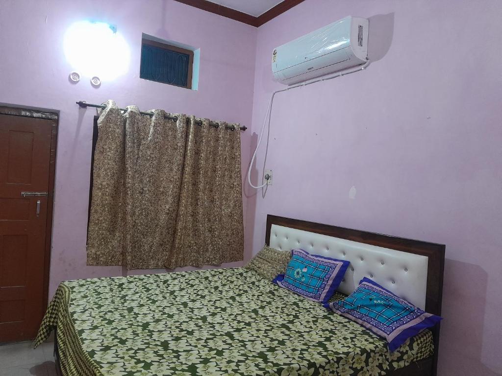 een slaapkamer met een bed met 2 kussens en een raam bij Ram priya gest house 5 mint waking Ram mandir in Ayodhya