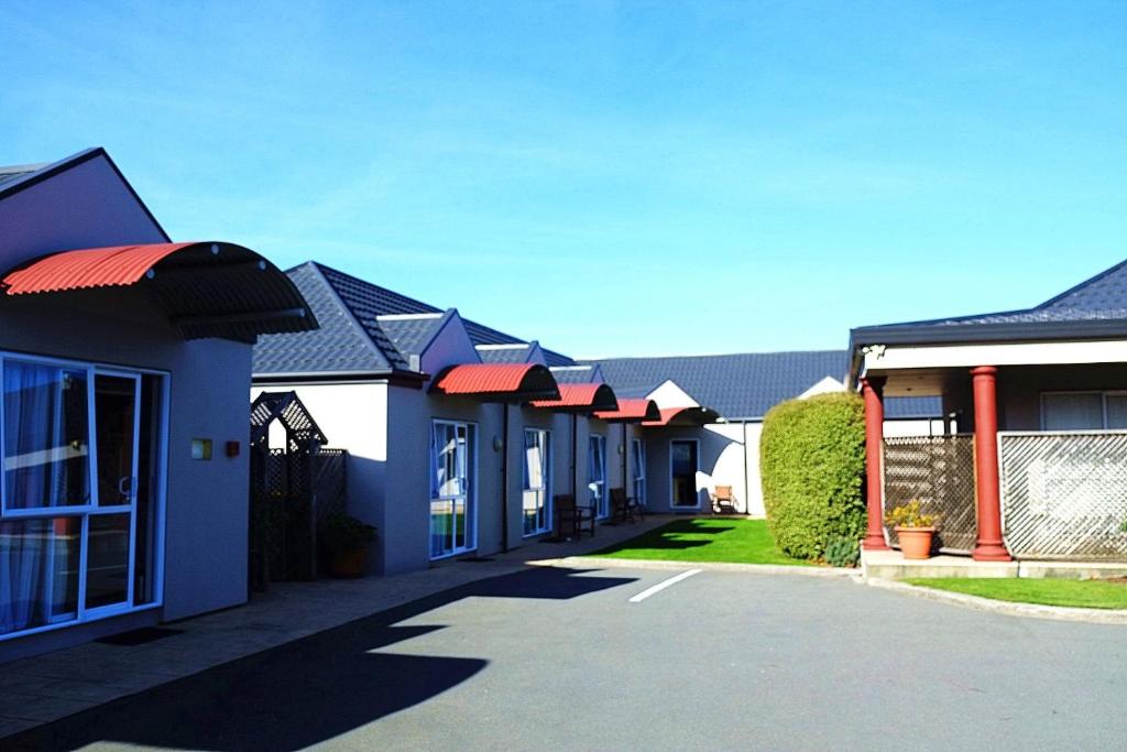 a blue and white building with umbrellas at Airport Birches Motel in Christchurch