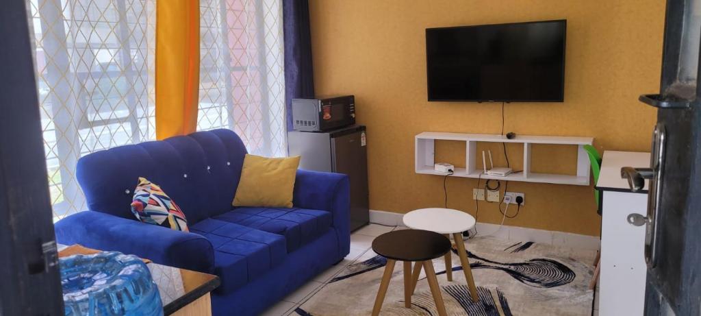 a living room with a blue couch and a tv at Elfiehomes in Nairobi