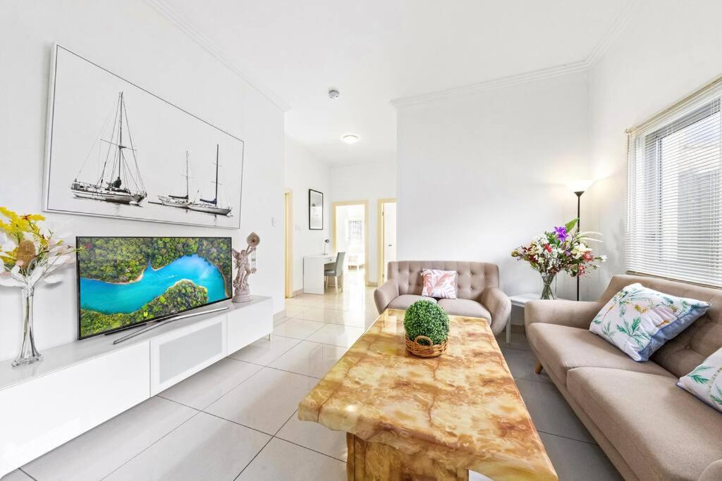 een woonkamer met een bank en een tv bij Cozy 4 Bedroom House at Prime Location in Sydney