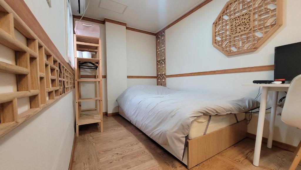 a small bedroom with a bed and a desk at Huesik Guesthouse in Seoul