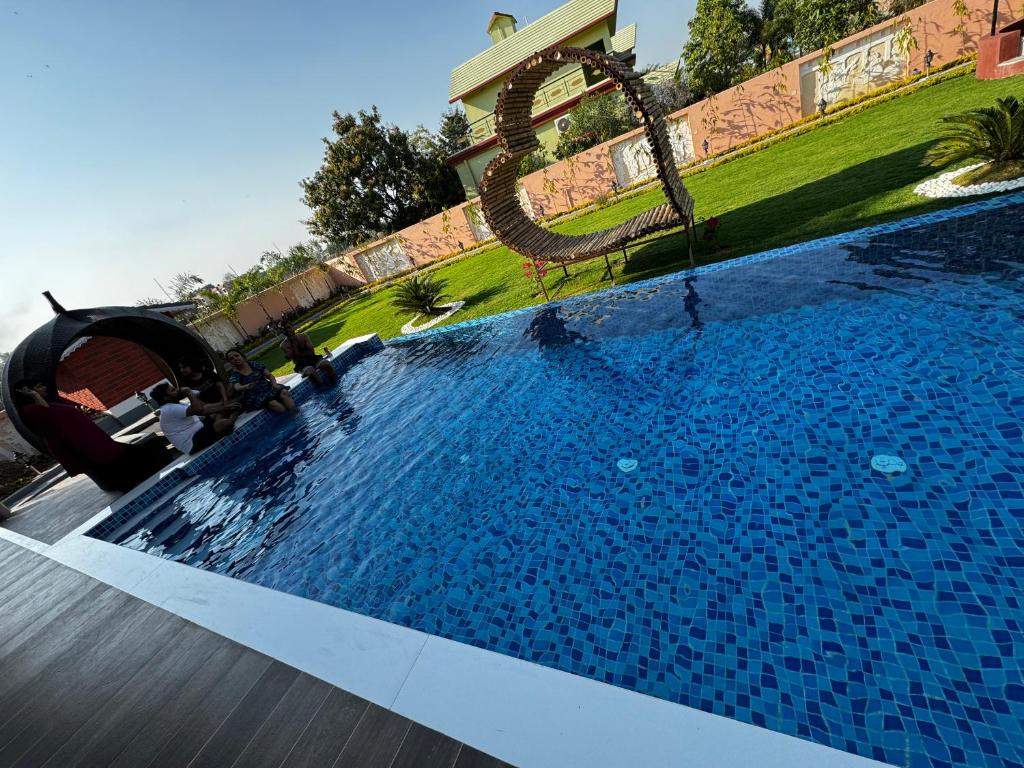 a large blue swimming pool with a swing at Chaitali The Villa in Shānti Niketan