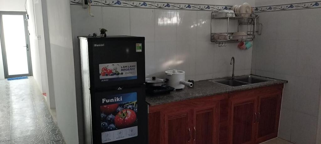 uma cozinha com um frigorífico preto e um lavatório em Đất Ninh Thuận 2 em Thôn Tân Hội