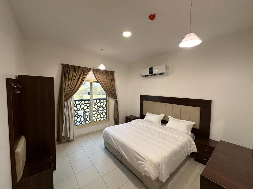 a bedroom with a white bed and a window at دبليو تاون للشقق المخدومة - W Town Serviced Apartments in Jeddah