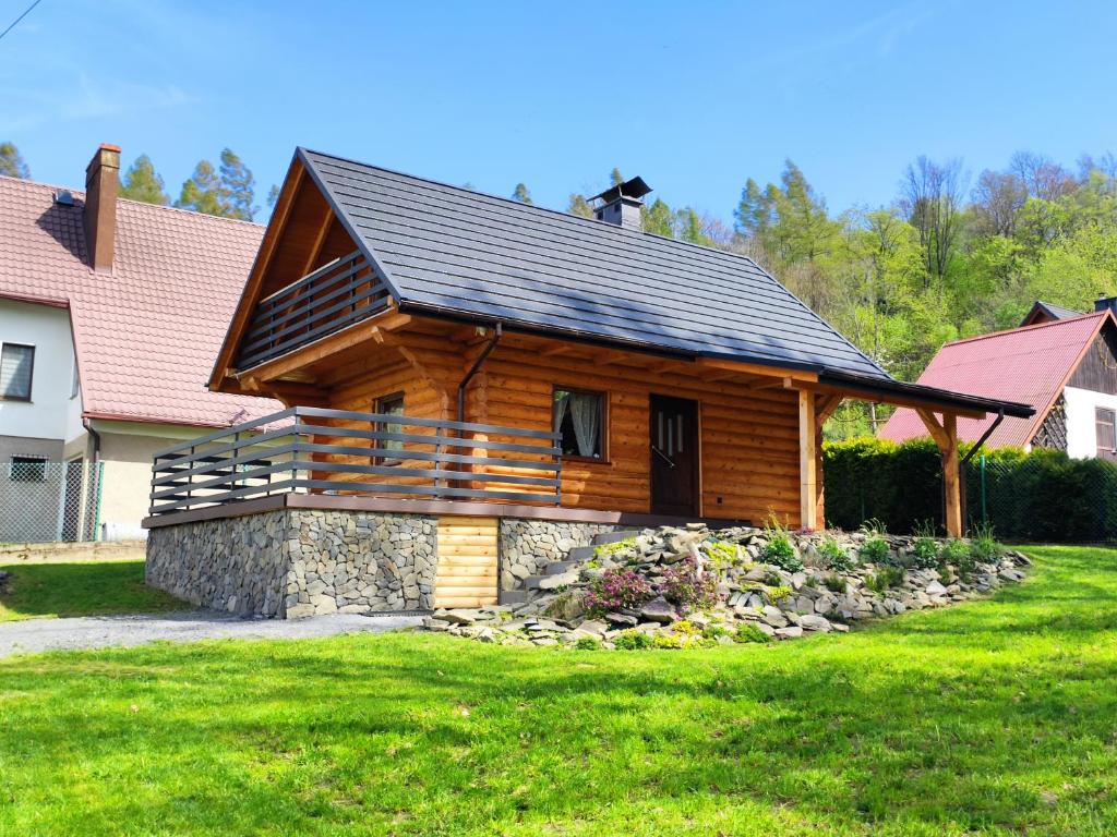 a log cabin with a black roof on a yard at Kwietna łąka na szlaku in Jarnołtówek
