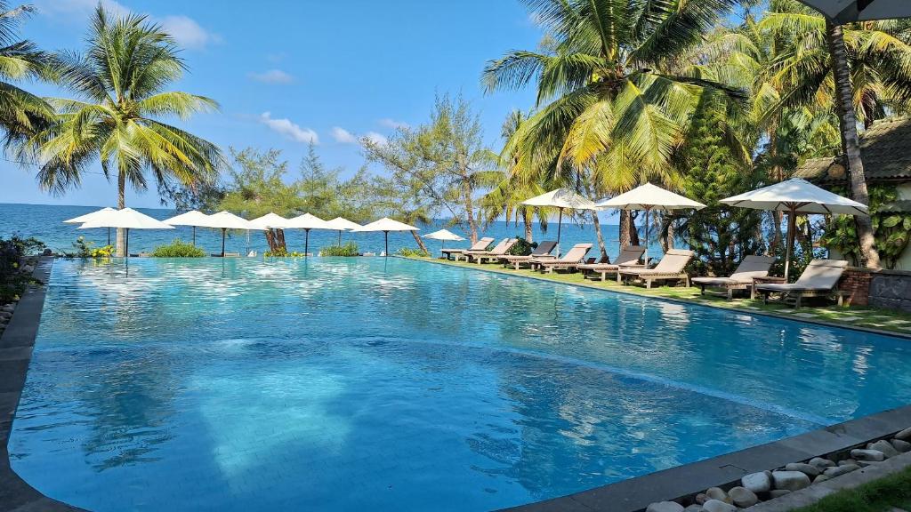 una gran piscina con sillas y sombrillas en Ancarine Beach Resort en Phu Quoc