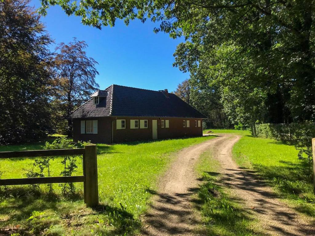 una casa su un campo verde vicino a una strada sterrata di Tussen Heide en Bos a Opglabbeek