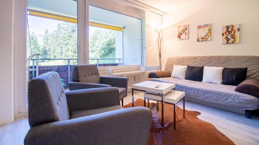 sala de estar con sofá, sillas y ventana en Rothornblick 6, en Arosa