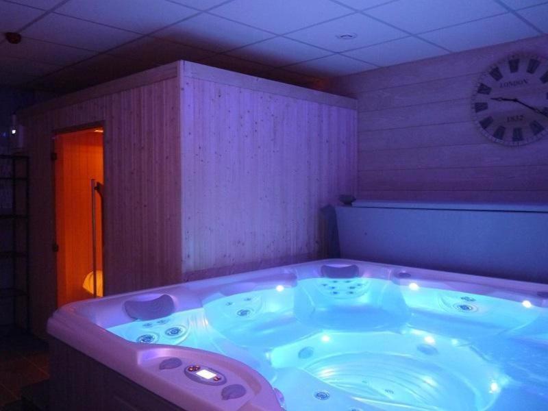 a jacuzzi tub in a room with a clock at LOVE SPA in Oye-Plage