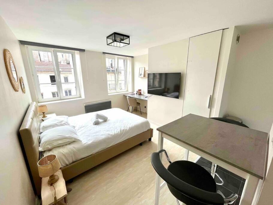 a bedroom with a bed and a table and a television at Le Studio Saint Georges in Nancy