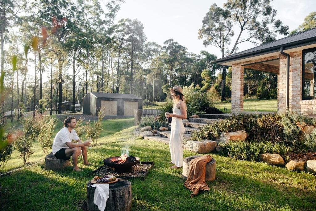 a man and a woman standing in a yard with a grill at Forever Sunday - Plunge Pool, Woodfire pizza oven, Outdoor firepit in Milton
