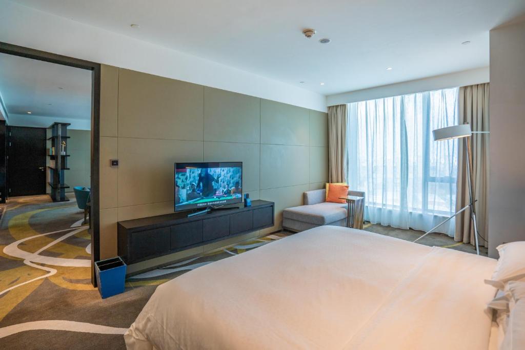 a hotel room with a large bed and a flat screen tv at Four Points by Sheraton Changchun Hi-Tech Zone in Changchun