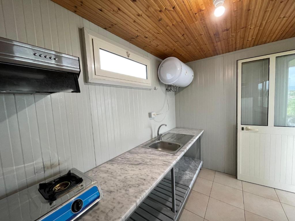 una pequeña cocina con fregadero y ventana en Garden Villa Sunny, en Tale