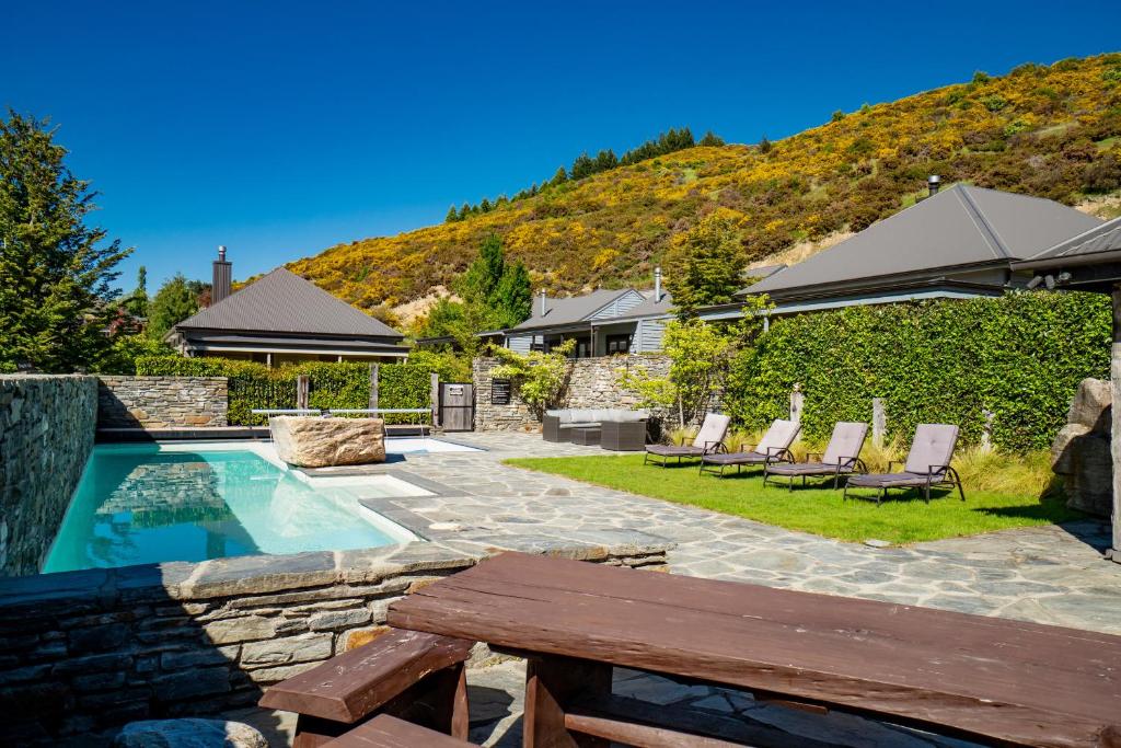 a backyard with a pool and chairs and a house at Valley Villa - Cardrona Holiday Home in Cardrona