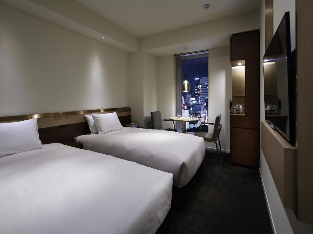 two beds in a hotel room with a window at Shinjuku Granbell Hotel in Tokyo