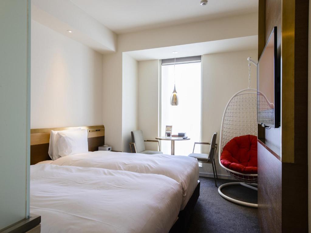 a hotel room with two beds and a red chair at Shinjuku Granbell Hotel in Tokyo