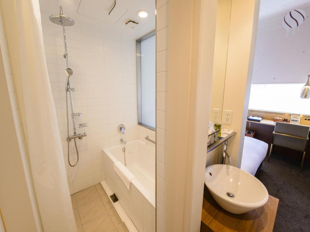a bathroom with a tub and a toilet and a sink at Shinjuku Granbell Hotel in Tokyo