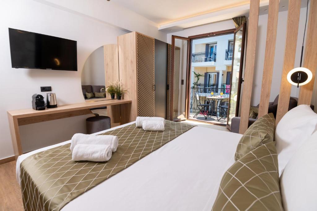 a bedroom with a bed with a desk and a window at John & Mary Suites in Rethymno