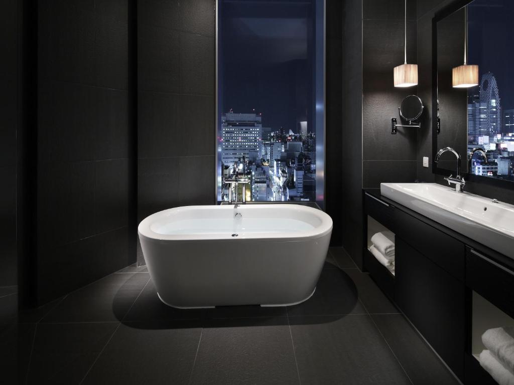 a bathroom with a bath tub and two sinks at Shinjuku Granbell Hotel in Tokyo