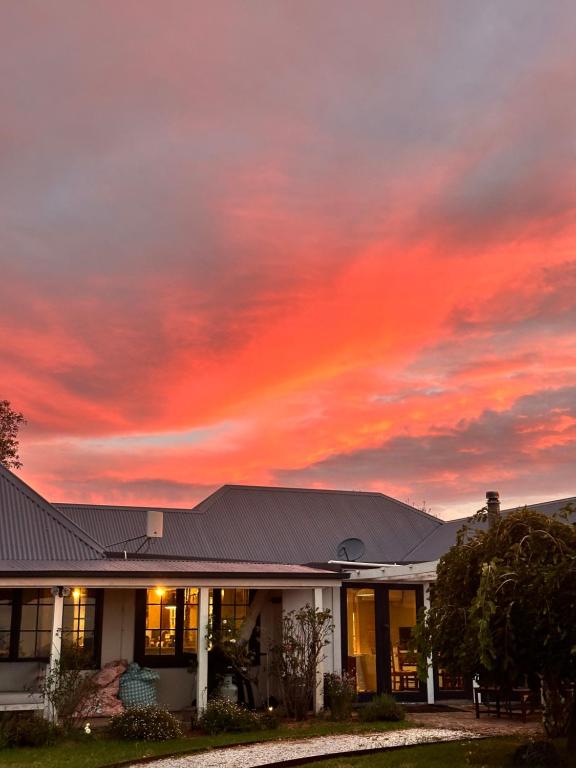 a building with a sunset in the sky at GARRU FARM…. A perfect rustic farm stay near Orange in Orange