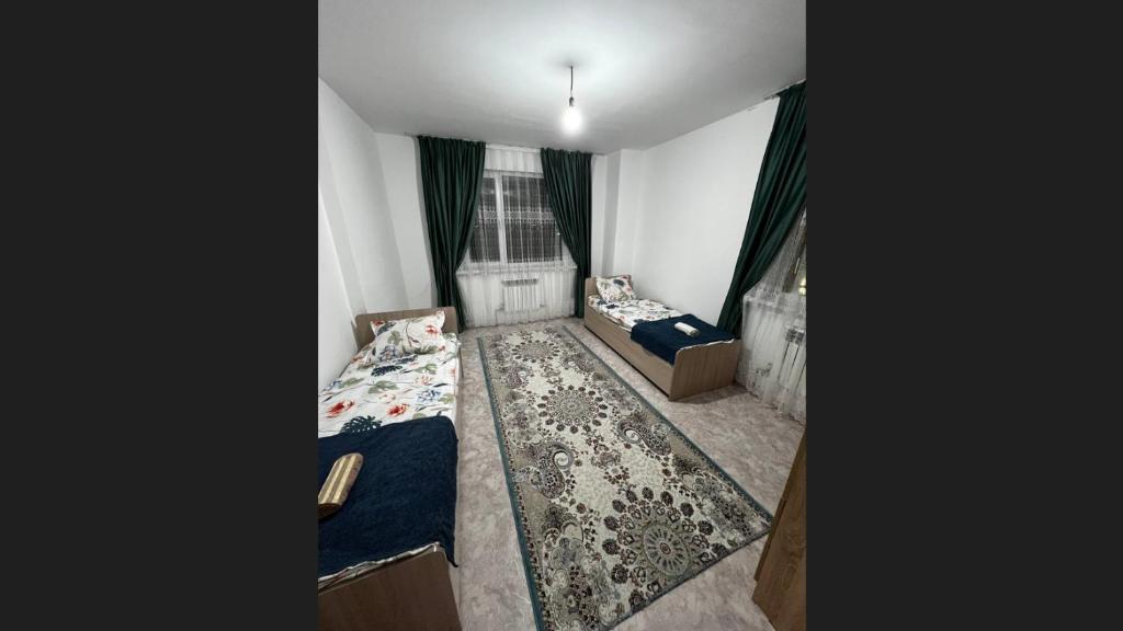 a small room with two beds and a window at 3 комнатная квартира in Türkistan
