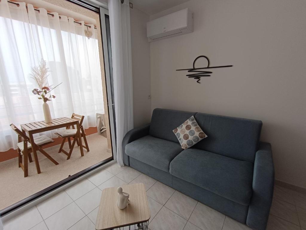 un salon avec un canapé bleu et une table dans l'établissement Le Petit Graulen, au Grau-du-Roi