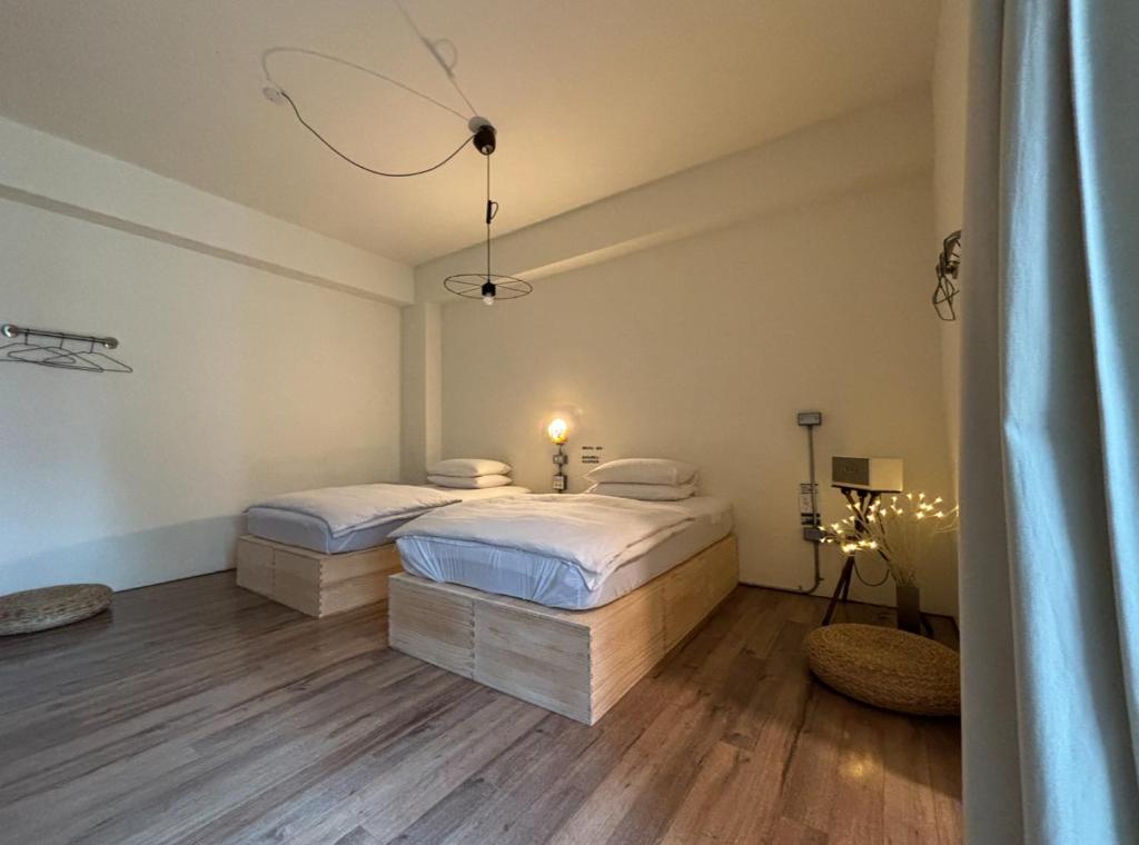 una camera con 2 letti, lenzuola bianche e pavimenti in legno di HomeStay LB a Città di Taitung