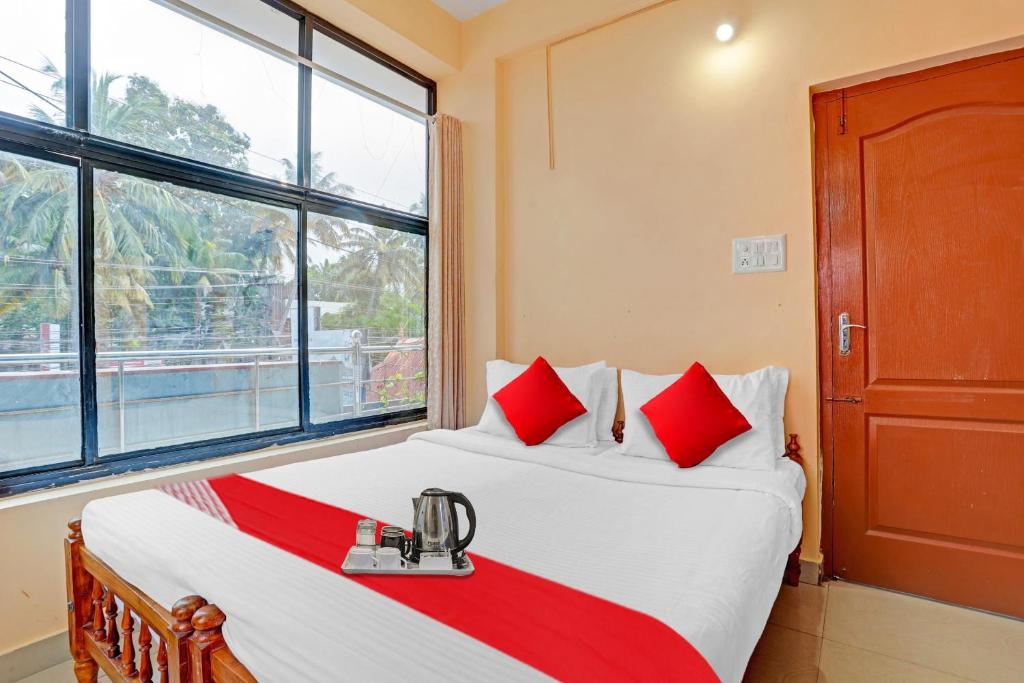 a bedroom with a bed with red pillows and a window at SPOT ON The New View Regency in Trivandrum