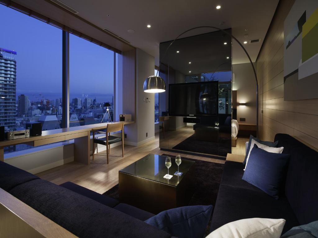a living room with a blue couch and a large window at Shinjuku Granbell Hotel in Tokyo