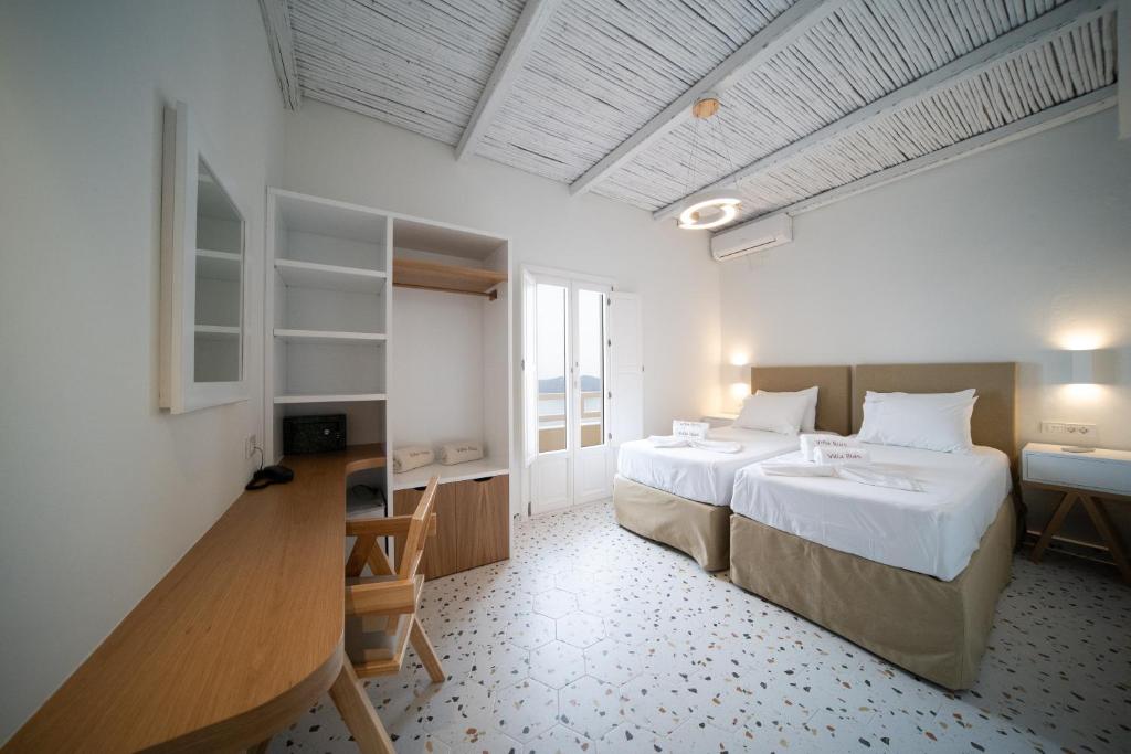 フィロステファニにあるヴィラ イリアスのベッドルーム1室(ベッド2台、テーブル、デスク付)
