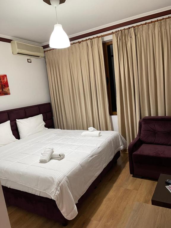Hotel Relax في غيروكاستر: غرفة نوم بسرير وكرسي ارجواني