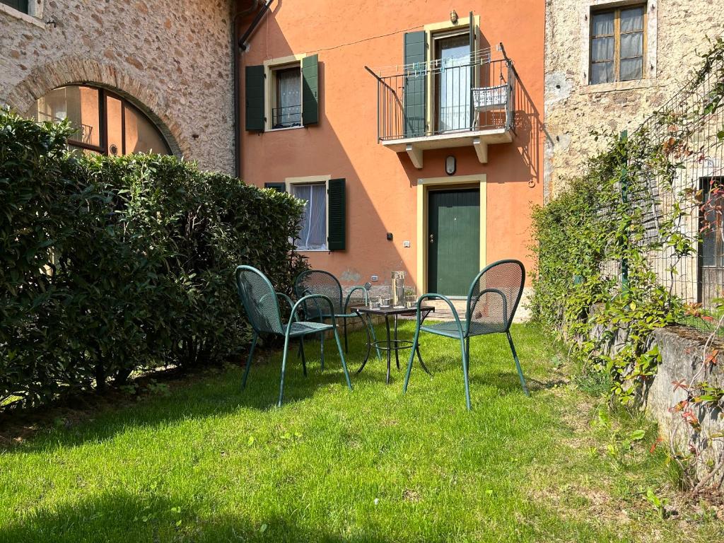 uma mesa e cadeiras na relva em frente a um edifício em Cozy Couples Apartment just 15 min from Garda Lake em Caprino Veronese
