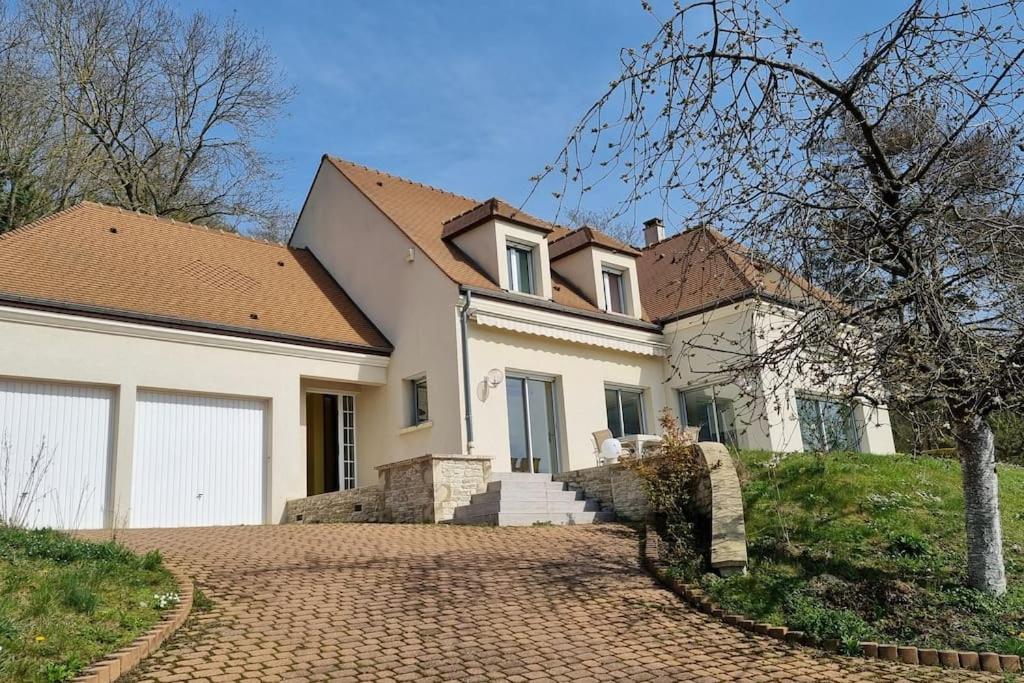 ein großes weißes Haus mit einer Ziegelsteinfahrt in der Unterkunft Calme et vue magnifique aux portes de Paris in Vaux-sur-Seine
