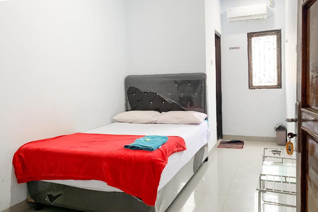 a bedroom with a bed with a red blanket on it at Penginapan Losmen Ayu Pamanukan RedPartner in Pamanukan-hilir