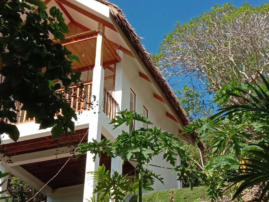 a white building with trees in front of it at MHARI Bungalows & Studio Rooms in Tubod