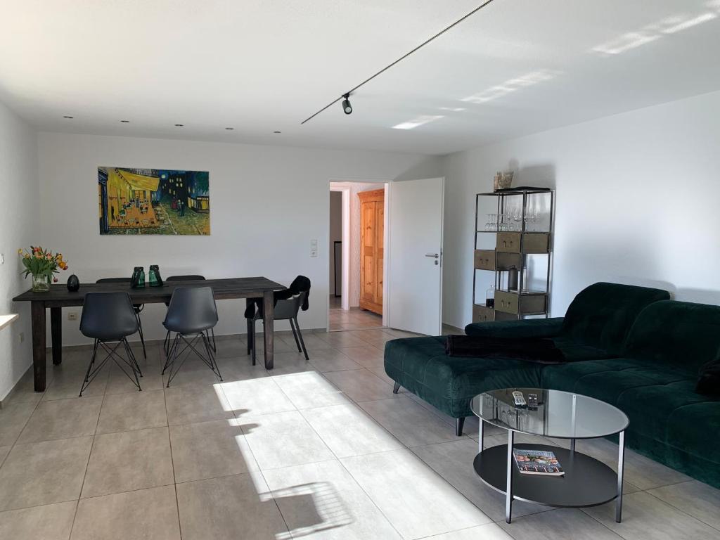 a living room with a green couch and a table at Ruhig, Sonnig und etwas Speziell in Hilzingen