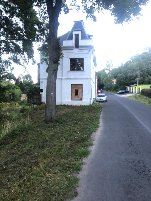 una casa blanca con un árbol al lado de una carretera en Die Blauer Stern Weipert en Chomutov