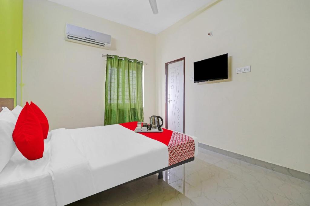 a bedroom with a white bed with red pillows and a television at Hotel Elite Stay Near Habsiguda Metro Station in Hyderabad