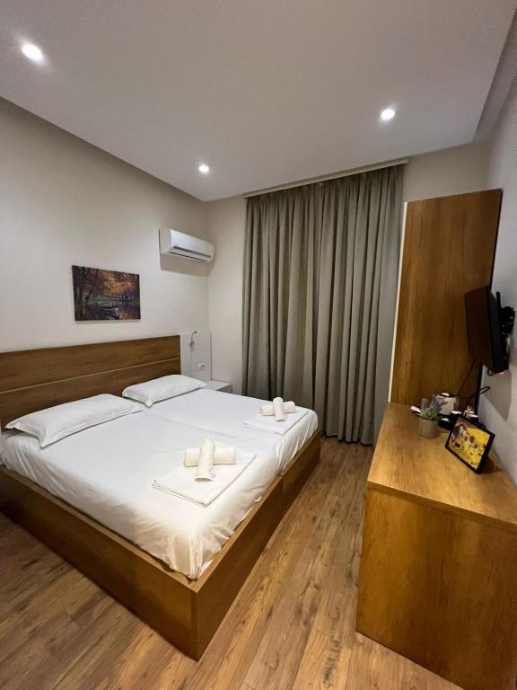 a bedroom with a bed with white sheets and a television at Urban Room 2 in Tirana