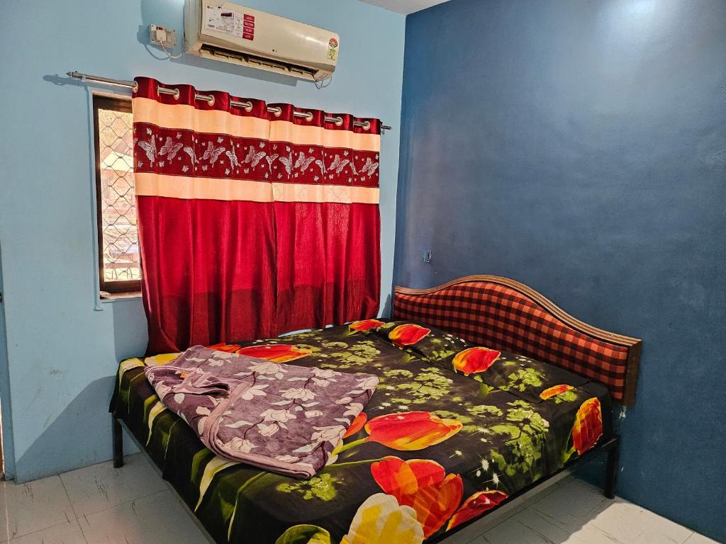 een bed in een kamer met een rood gordijn bij New Aashiyana Cottage in Matheran