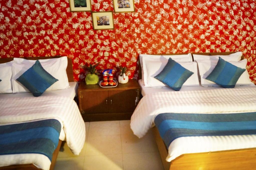 a bedroom with two beds and a red wall at Hotel HRS - New Delhi Railway Station in New Delhi
