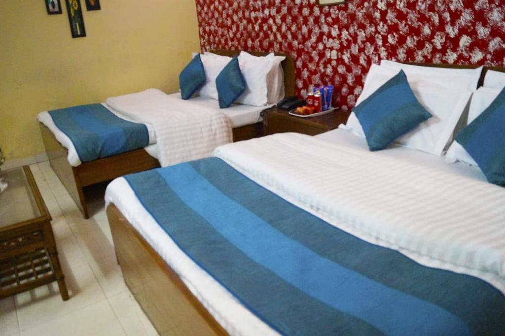 a hotel room with two beds with blue and white sheets at Hotel HRS - New Delhi Railway Station in New Delhi