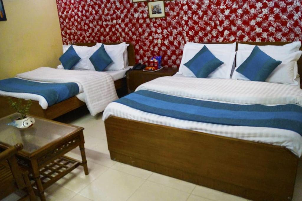 a bedroom with two beds with blue and white pillows at Hotel HRS - New Delhi Railway Station in New Delhi