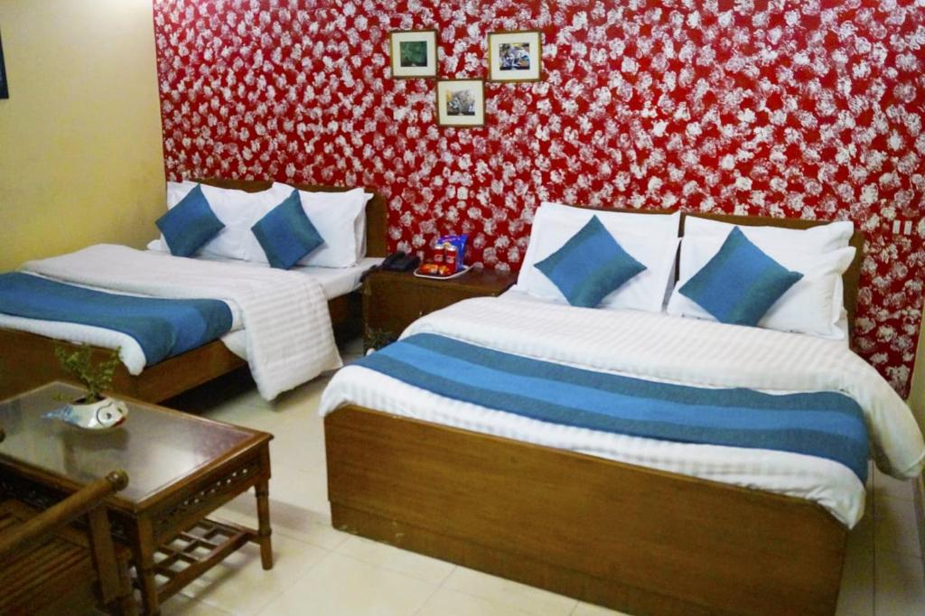 a bedroom with two beds and a red and white wall at Hotel HRS - New Delhi Railway Station in New Delhi