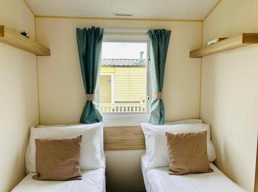 2 Betten in einem kleinen Zimmer mit Fenster in der Unterkunft The salsa golden gate towyn in Kinmel Bay