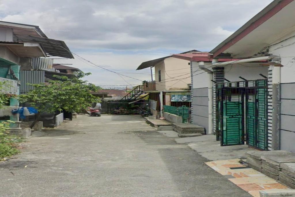 棉蘭的住宿－SPOT ON 93851 Fermansio Homestay 1，两座建筑之间的小巷,有绿门