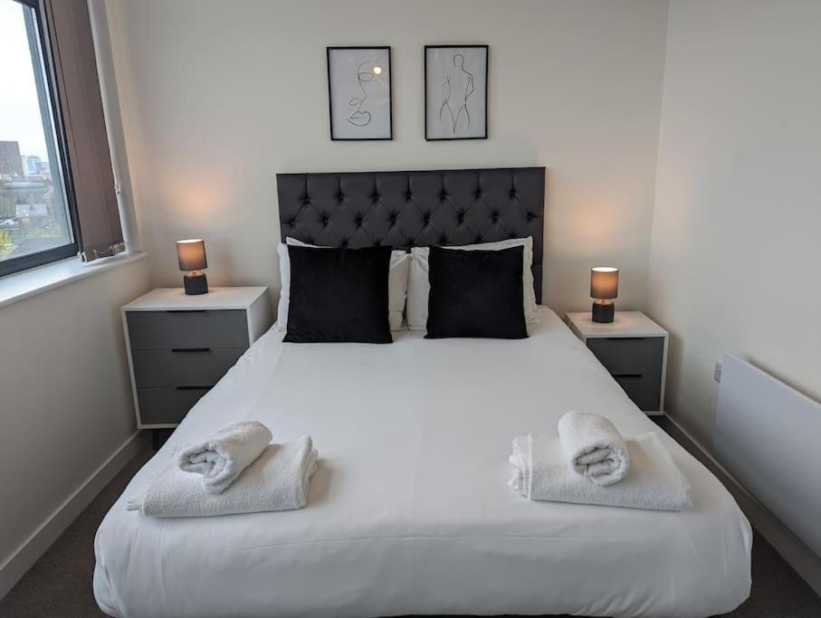 um quarto com uma grande cama branca com toalhas em Lovely 1 Bed Apartment - Old Trafford em Manchester
