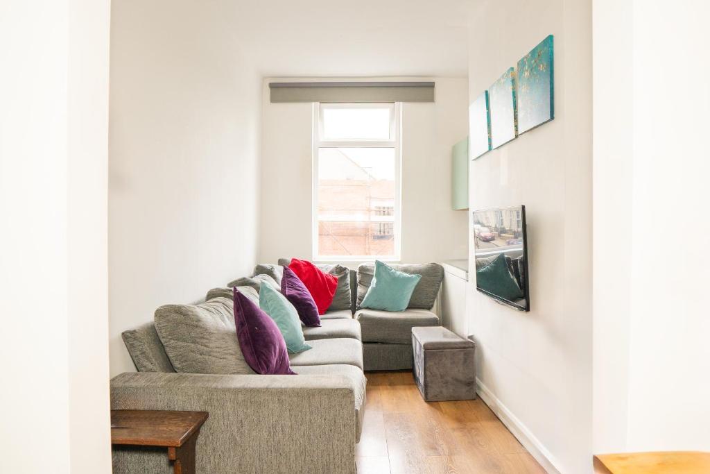 a living room with a couch with colorful pillows at Blue Nile Apartment - Liverpool in Liverpool