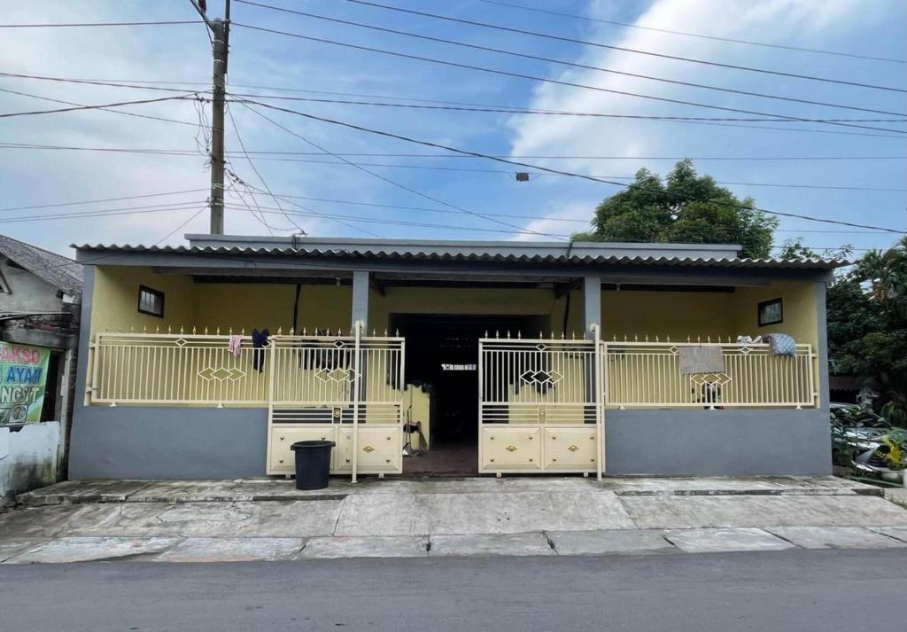 una piccola casa gialla con un cancello di fronte di SPOT ON 93879 Wunut Homestay Syariah a Sidoarjo